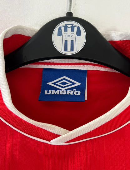 Maillot de foot vintage domicile rouge et blanc de l'Ajax Amsterdam saison 1999/2000. On peut retrouver l'équipementier Umbro et le sponsor ABN-AMRO. Il s'agit d'un maillot authentique d'époque issu du stock pro.