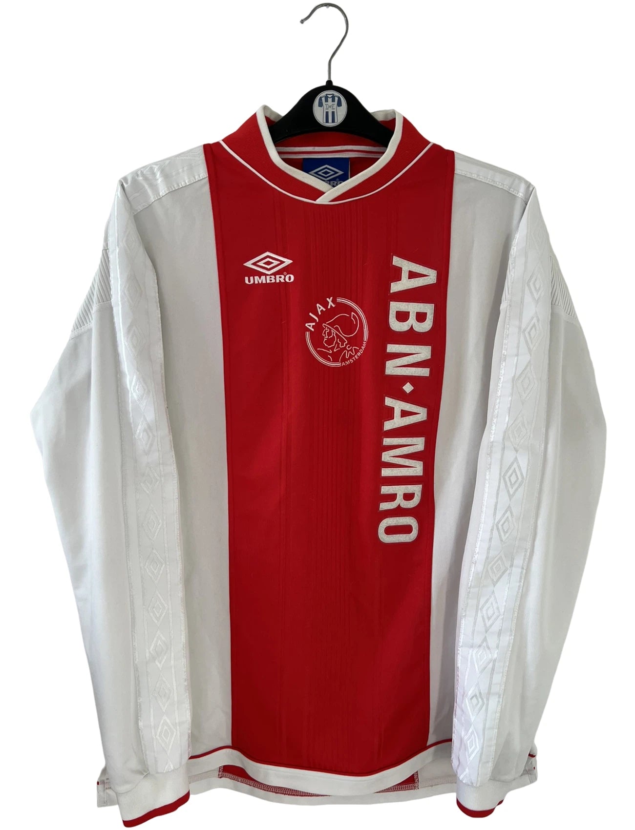 Maillot de foot vintage domicile rouge et blanc de l'Ajax Amsterdam saison 1999/2000. On peut retrouver l'équipementier Umbro et le sponsor ABN-AMRO. Il s'agit d'un maillot authentique d'époque issu du stock pro.