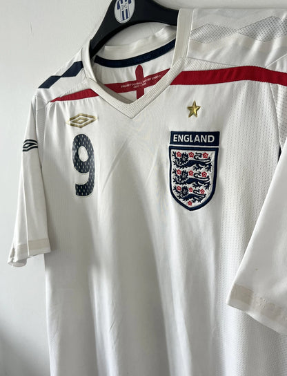 Maillot de foot vintage domicile blanc de l'Angleterre de la saison 2008-2009. On peut y retrouver l'équipementier Umbro. Le maillot est floqué du numéro 9 Rooney. Il s'agit d'un maillot authentique d'époque