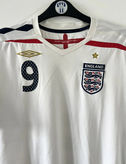 Maillot de foot vintage domicile blanc de l'Angleterre de la saison 2008-2009. On peut y retrouver l'équipementier Umbro. Le maillot est floqué du numéro 9 Rooney. Il s'agit d'un maillot authentique d'époque