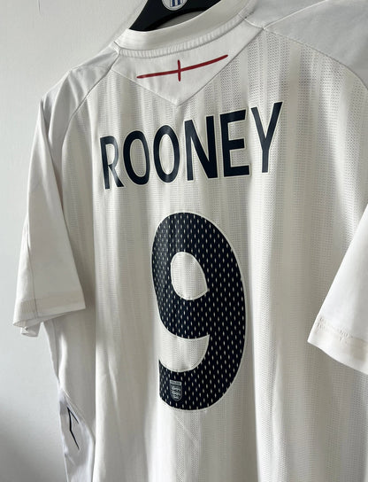 Maillot de foot vintage domicile blanc de l'Angleterre de la saison 2008-2009. On peut y retrouver l'équipementier Umbro. Le maillot est floqué du numéro 9 Rooney. Il s'agit d'un maillot authentique d'époque