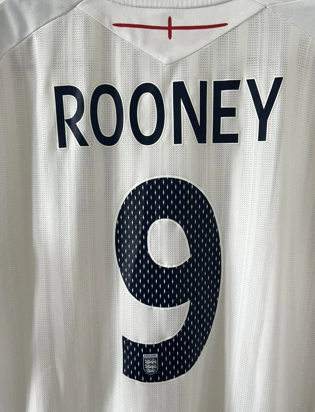 Maillot de foot vintage domicile blanc de l'Angleterre de la saison 2008-2009. On peut y retrouver l'équipementier Umbro. Le maillot est floqué du numéro 9 Rooney. Il s'agit d'un maillot authentique d'époque