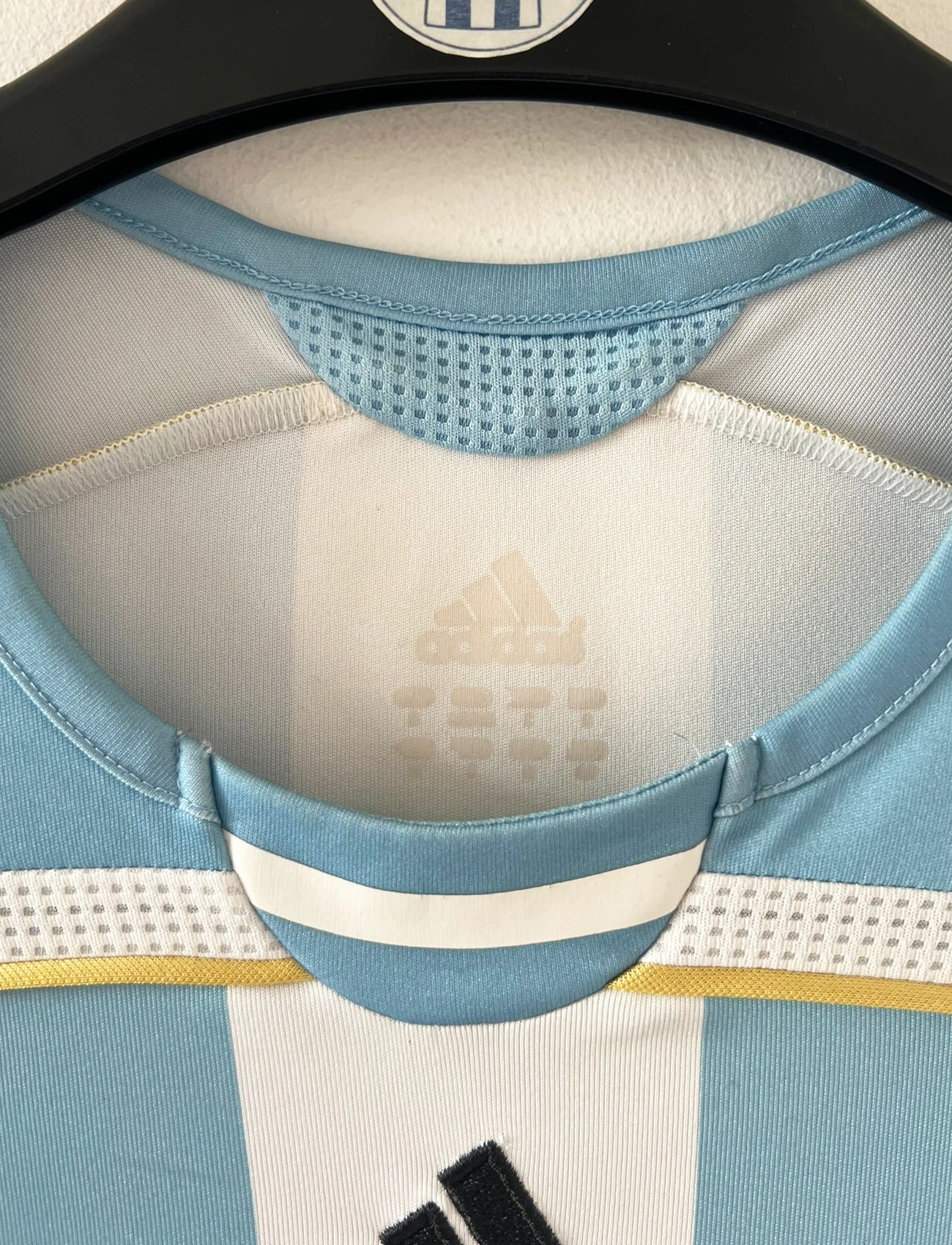 Maillot de foot vintage domicile de l'Argentine 2006. On peut retrouver l'équipementier Adidas. Le maillot est floqué du numéro 19 Messi. Il s'agit d'un maillot authentique d'époque.