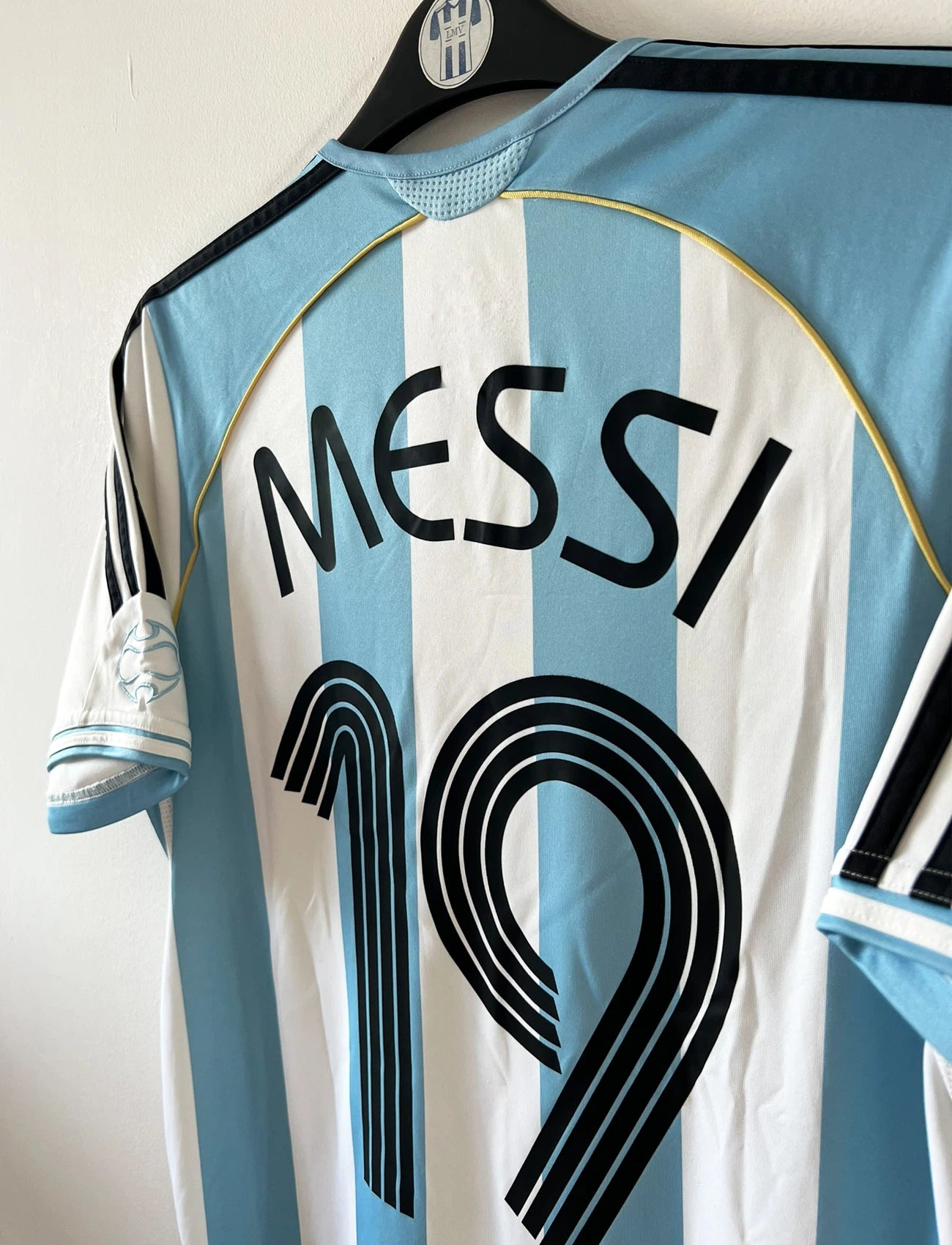 Maillot de foot vintage domicile de l'Argentine 2006. On peut retrouver l'équipementier Adidas. Le maillot est floqué du numéro 19 Messi. Il s'agit d'un maillot authentique d'époque.