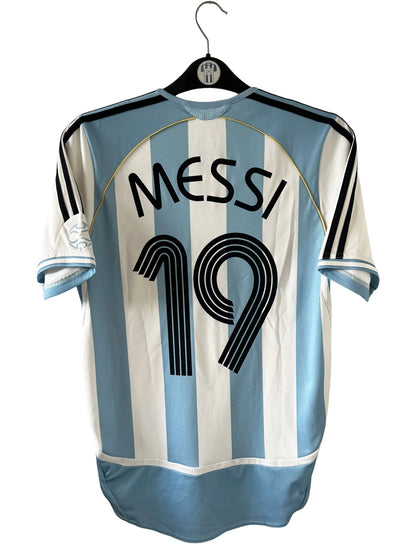 Maillot de foot vintage domicile de l'Argentine 2006. On peut retrouver l'équipementier Adidas. Le maillot est floqué du numéro 19 Messi. Il s'agit d'un maillot authentique d'époque.