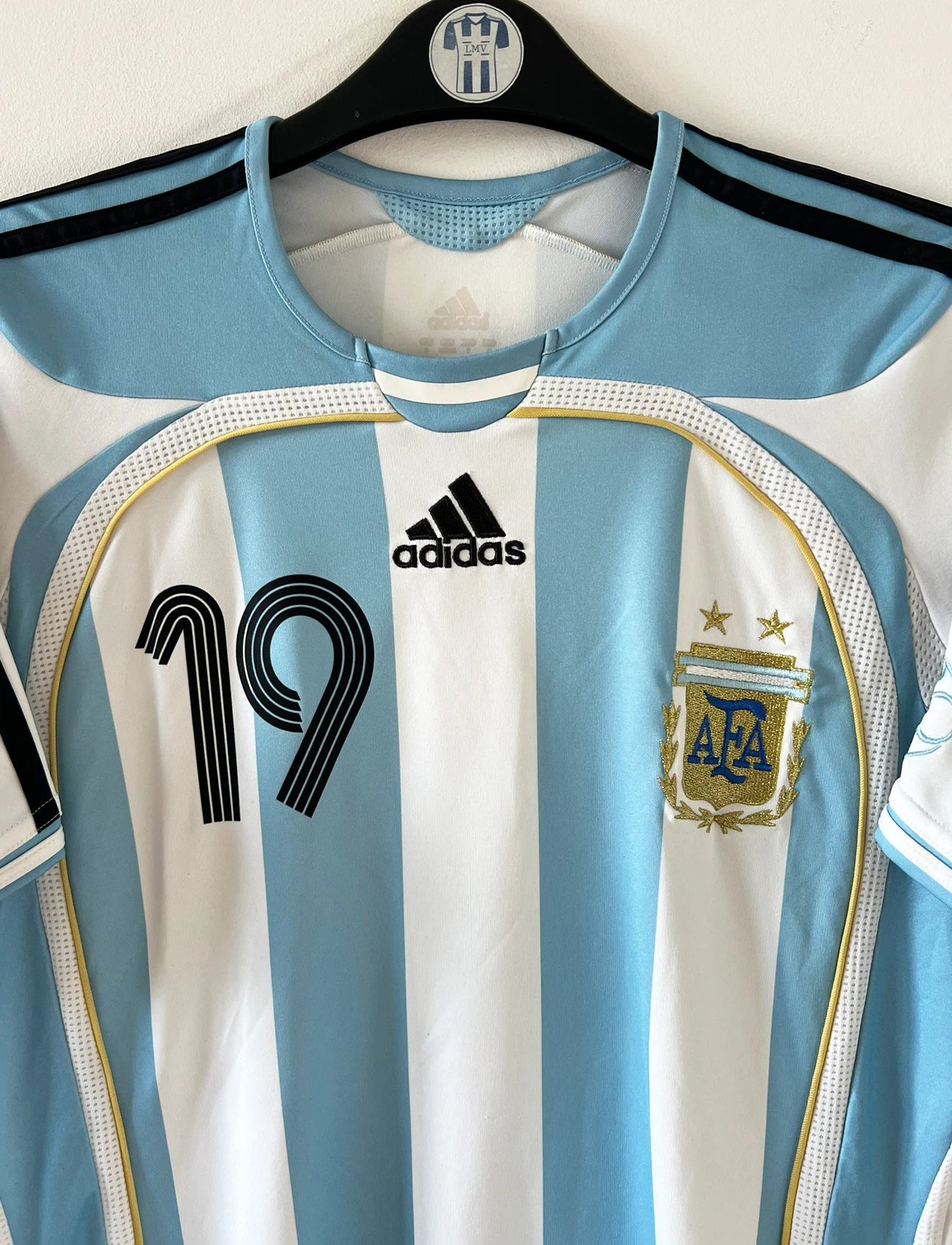 Maillot de foot vintage domicile de l'Argentine 2006. On peut retrouver l'équipementier Adidas. Le maillot est floqué du numéro 19 Messi. Il s'agit d'un maillot authentique d'époque.