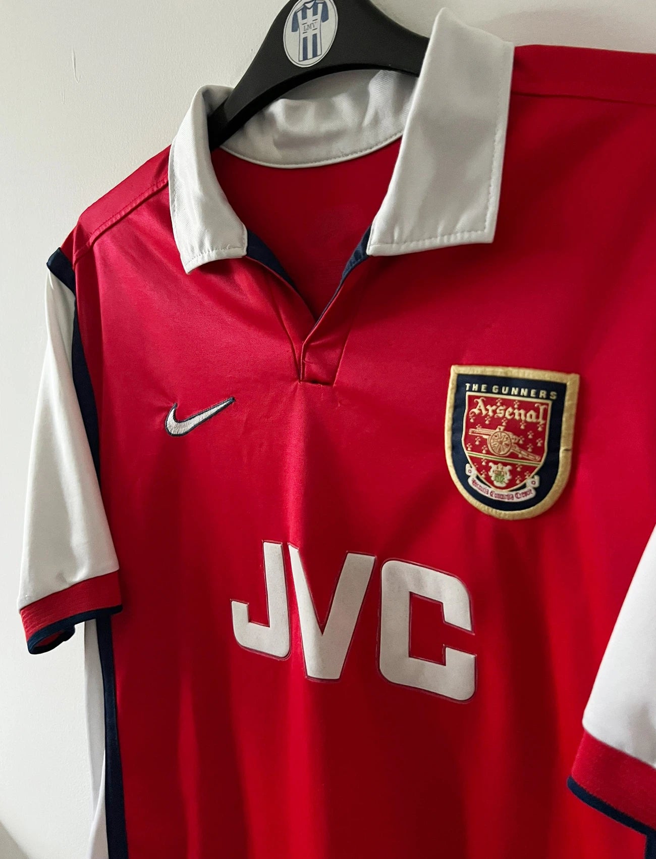 Maillot de foot vintage domicile rouge et blanc d'arsenal de la saison 1998/1999. On peut retrouver l'équipementier Nike et le sponsor JVC. Le maillot est floqué du numéro 10 Dennis Bergkamp. Il s'agit d'un maillot authentique d'époque.