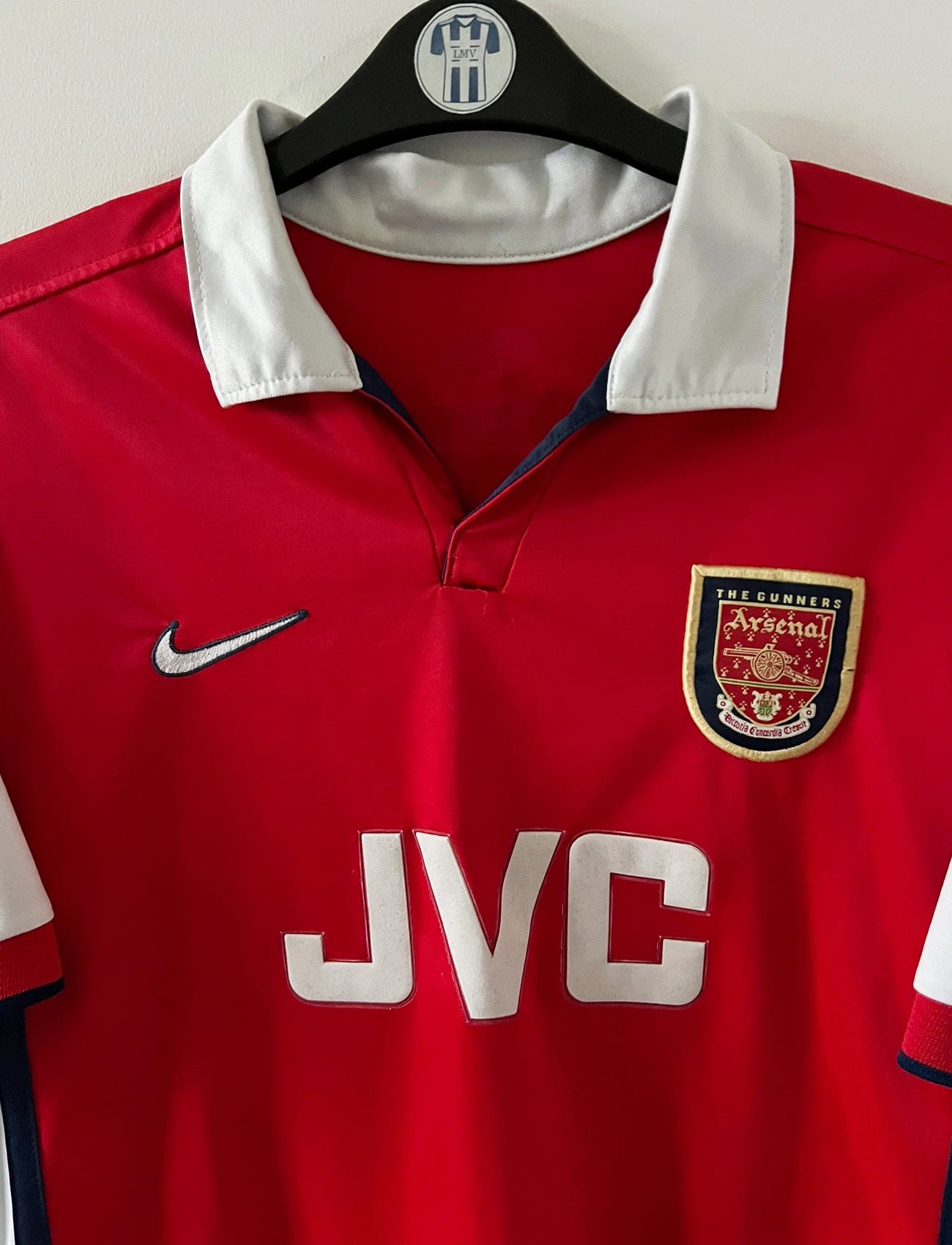 Maillot de foot vintage domicile rouge et blanc d'arsenal de la saison 1998/1999. On peut retrouver l'équipementier Nike et le sponsor JVC. Le maillot est floqué du numéro 10 Dennis Bergkamp. Il s'agit d'un maillot authentique d'époque.