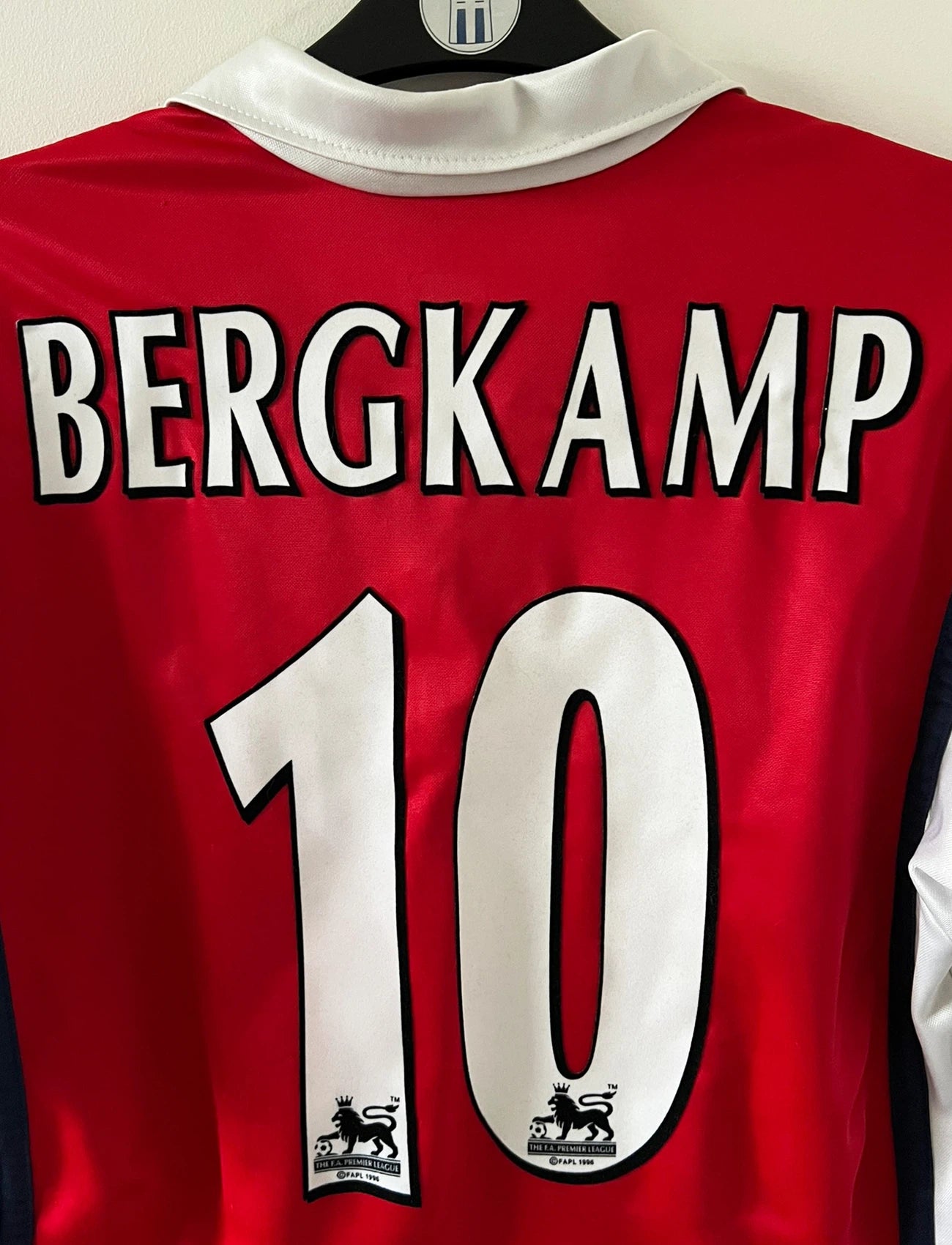 Maillot de foot vintage domicile rouge et blanc d'arsenal de la saison 1998/1999. On peut retrouver l'équipementier Nike et le sponsor JVC. Le maillot est floqué du numéro 10 Dennis Bergkamp. Il s'agit d'un maillot authentique d'époque.