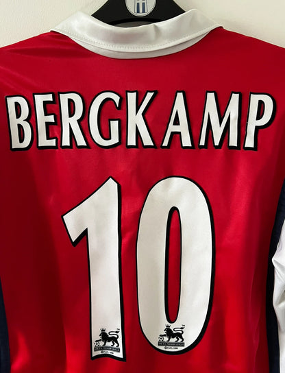 Maillot de foot vintage domicile rouge et blanc d'arsenal de la saison 1998/1999. On peut retrouver l'équipementier Nike et le sponsor JVC. Le maillot est floqué du numéro 10 Dennis Bergkamp. Il s'agit d'un maillot authentique d'époque.