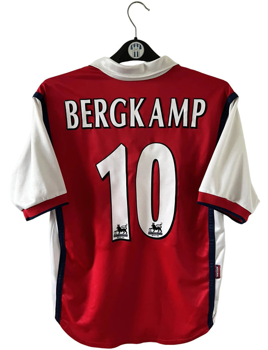 Maillot de foot vintage domicile rouge et blanc d'arsenal de la saison 1998/1999. On peut retrouver l'équipementier Nike et le sponsor JVC. Le maillot est floqué du numéro 10 Dennis Bergkamp. Il s'agit d'un maillot authentique d'époque.