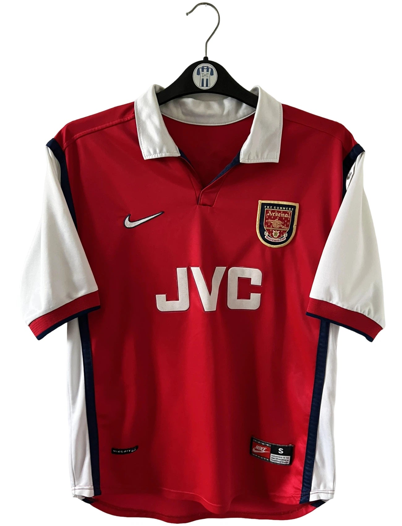 Maillot de foot vintage domicile rouge et blanc d'arsenal de la saison 1998/1999. On peut retrouver l'équipementier Nike et le sponsor JVC. Le maillot est floqué du numéro 10 Dennis Bergkamp. Il s'agit d'un maillot authentique d'époque.