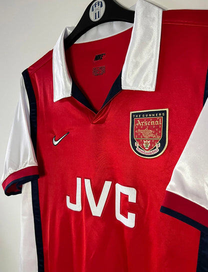 Maillot de foot vintage domicile rouge et blanc d'Arsenal de la saison 1998/1999. On peut retrouver l'équipementier Nike et le sponsor JVC. Il s'agit d'un maillot authentique d'époque.