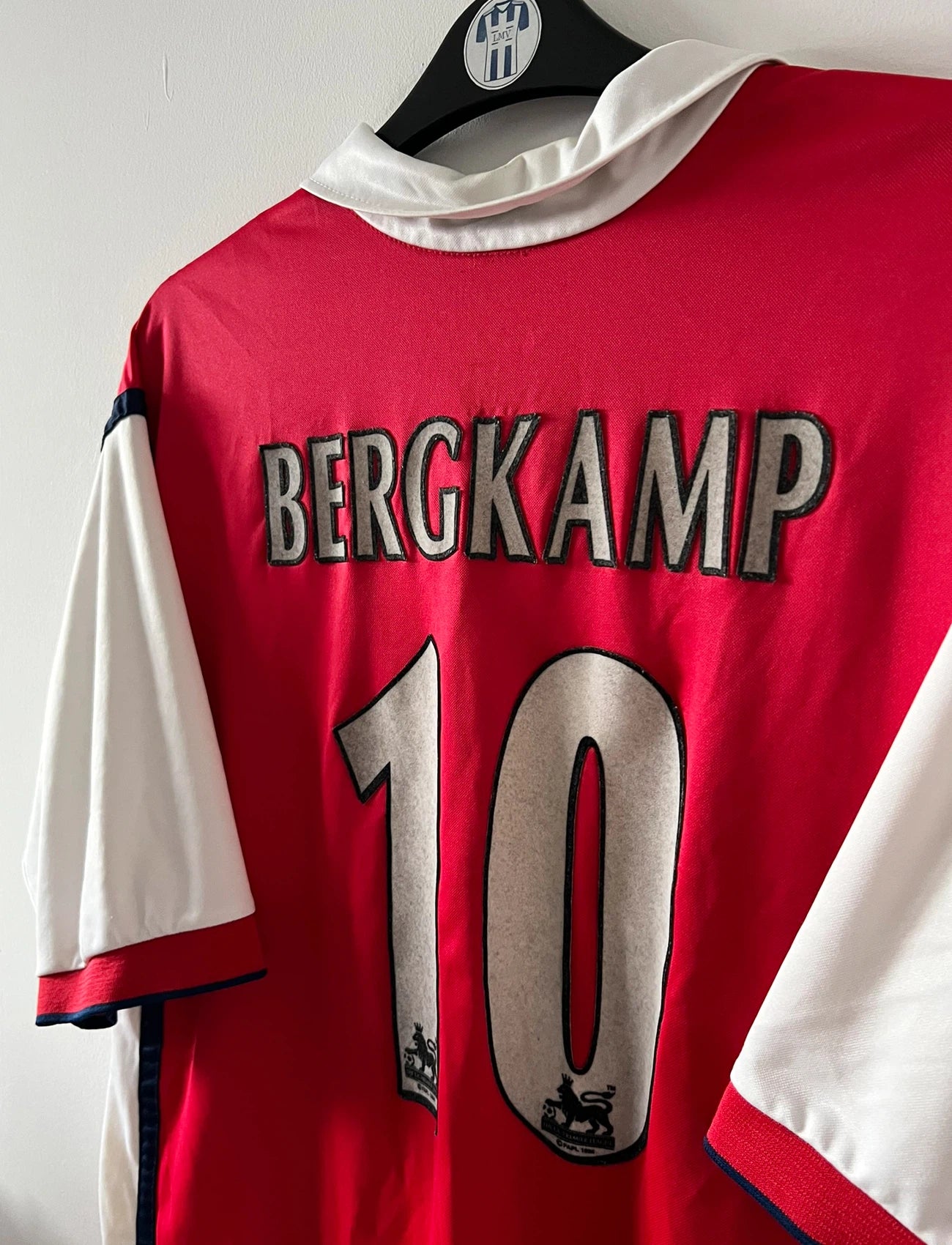 Maillot de foot vintage domicile rouge et blanc d'arsenal de la saison 1999/2000. On peut retrouver l'équipementier Nike et le sponsor JVC. Le maillot est floqué du numéro 10 Dennis Bergkamp. Il s'agit d'un maillot authentique d'époque.