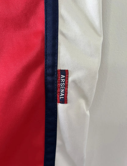 Maillot de foot vintage domicile rouge d'arsenal de la saison 1999/2000. On peut retrouver l'équipementier Nike et le sponsor Dreamcast. Le maillot est floqué du numéro 11 Marc Overmars. Il s'agit d'un maillot authentique d'époque.