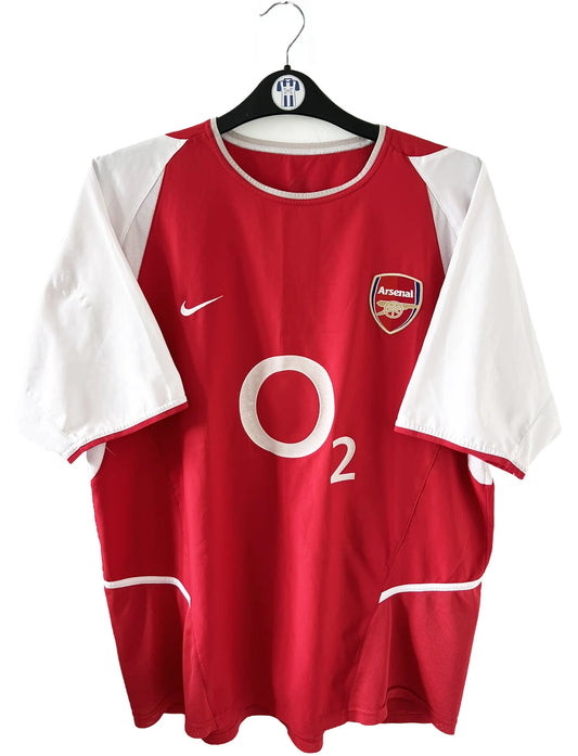 Maillot domicile Arsenal rouge et blanc de la saison 2002-2004. On peut retrouver l'équipementier nike et le sponsor O2. Il s'agit d'un maillot authentique d'époque comportant l'étiquette 184985