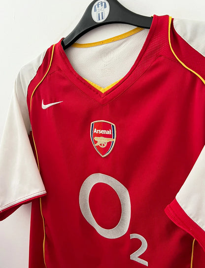 Maillot de foot vintage domicile rouge et blanc d'Arsenal 2004/2005. On peut retrouver l'équipementier Nike et le sponsor O2. Il s'agit d'un maillot authentique d'époque.