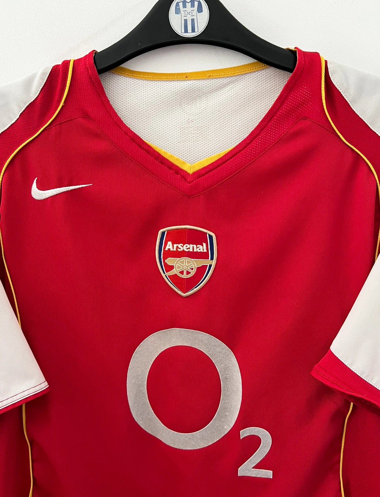 Maillot de foot vintage domicile rouge et blanc d'Arsenal 2004/2005. On peut retrouver l'équipementier Nike et le sponsor O2. Il s'agit d'un maillot authentique d'époque.