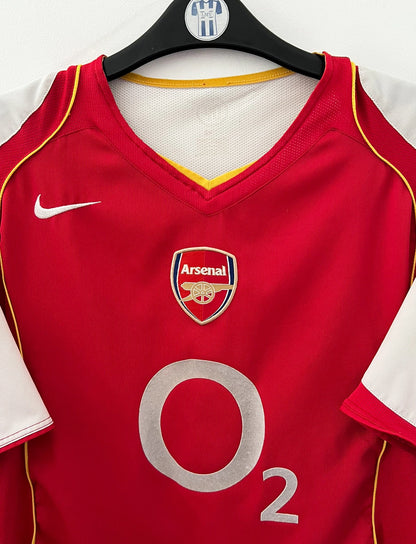 Maillot de foot vintage domicile rouge et blanc d'Arsenal 2004/2005. On peut retrouver l'équipementier Nike et le sponsor O2. Il s'agit d'un maillot authentique d'époque.