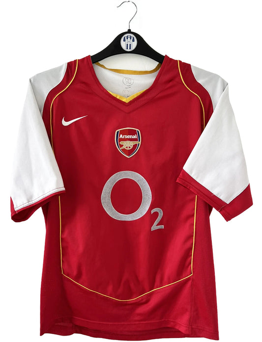 Maillot de foot vintage domicile d'arsenal de la saison 2004/2005. Le maillot est de couleur rouge et blanc. On peut retrouver l'équipementier nike et le sponsor O2 en feutrine. Il s'agit d'un maillot authentique d'époque.