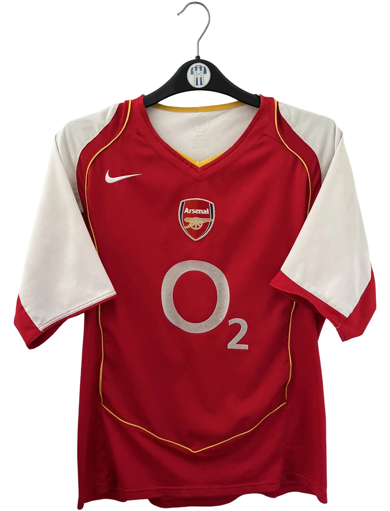 Maillot de foot vintage domicile rouge et blanc d'Arsenal 2004/2005. On peut retrouver l'équipementier Nike et le sponsor O2. Il s'agit d'un maillot authentique d'époque.