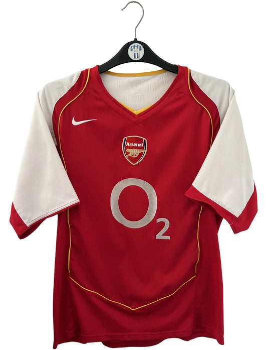 Maillot de foot vintage domicile rouge et blanc d'Arsenal 2004/2005. On peut retrouver l'équipementier Nike et le sponsor O2. Il s'agit d'un maillot authentique d'époque.