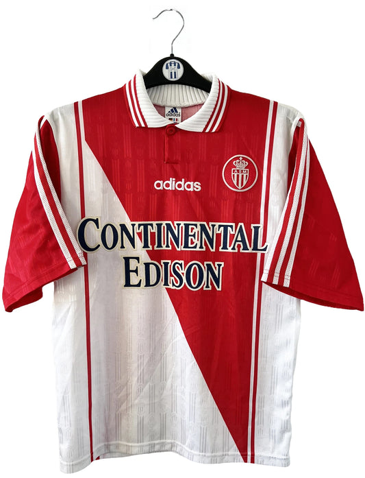 Maillot de foot vintage domicile rouge et blanc de l'AS Monaco de la saison 1997/1998. On peut retrouver l'équipementier Adidas et le sponsor Continental Edison. Il s'agit d'un maillot authentique d'époque.