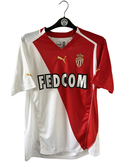 Maillot de foot vintage domicile blanc et rouge de l'as monaco 2004/2006. On peut retrouver l'équipementier Puma et le sponsor Fedcom. Il s'agit d'un maillot authentique d'époque.