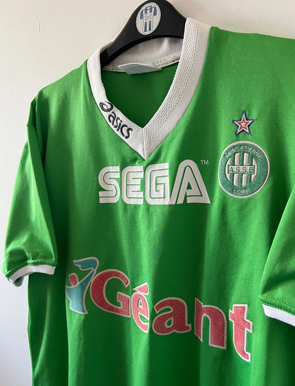 Maillot de foot vintage domicile vert de l'ASSE 1999/2000. On peut retrouver l'équipementier Asics et le sponsor Sega et Géant Casino. Il s'agit d'un maillot authentique d'époque.