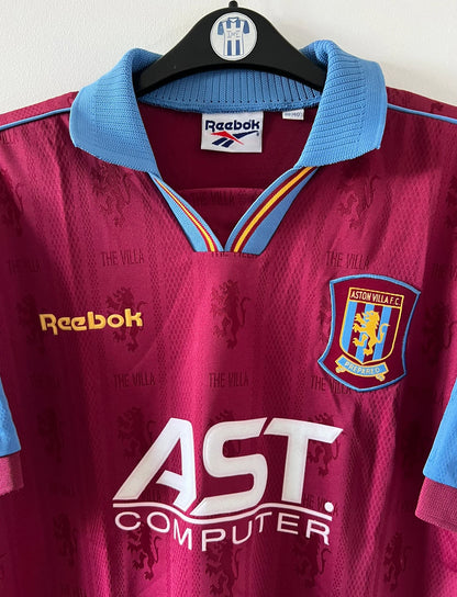 Maillot de foot vintage domicile rouge et bleu d'aston villa de la saison 1995/1997. On peut retrouver l'équipementier Reebok et le sponsor AST Computer. Il s'agit d'un maillot authentique d'époque.