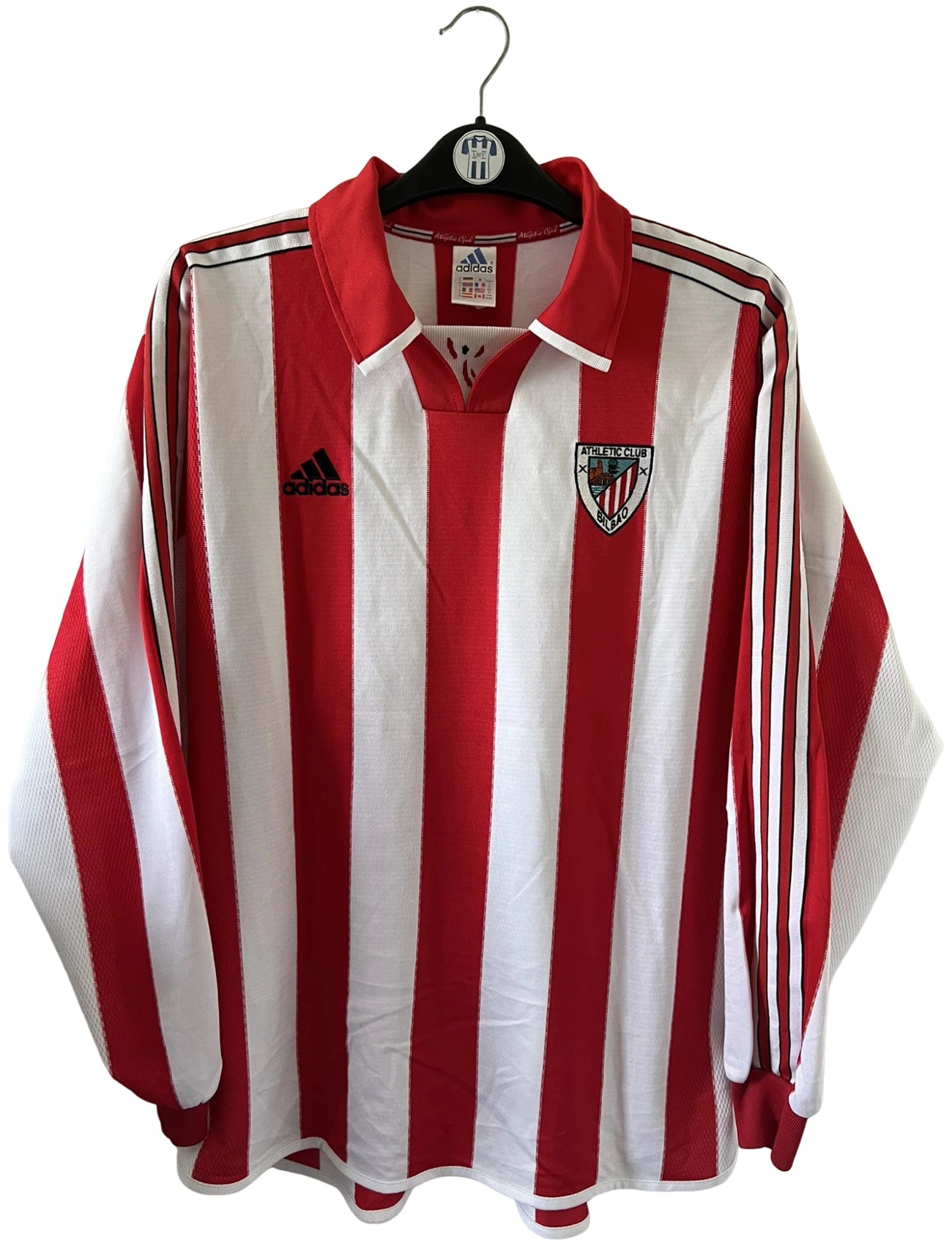 Maillot de foot vintage domicile rouge et blanc de l'Athletic Bilbao de la saison 1999/2001. On peut retrouver l'équipementier Adidas. Il s'agit d'un maillot authentique d'époque issu du stock pro.