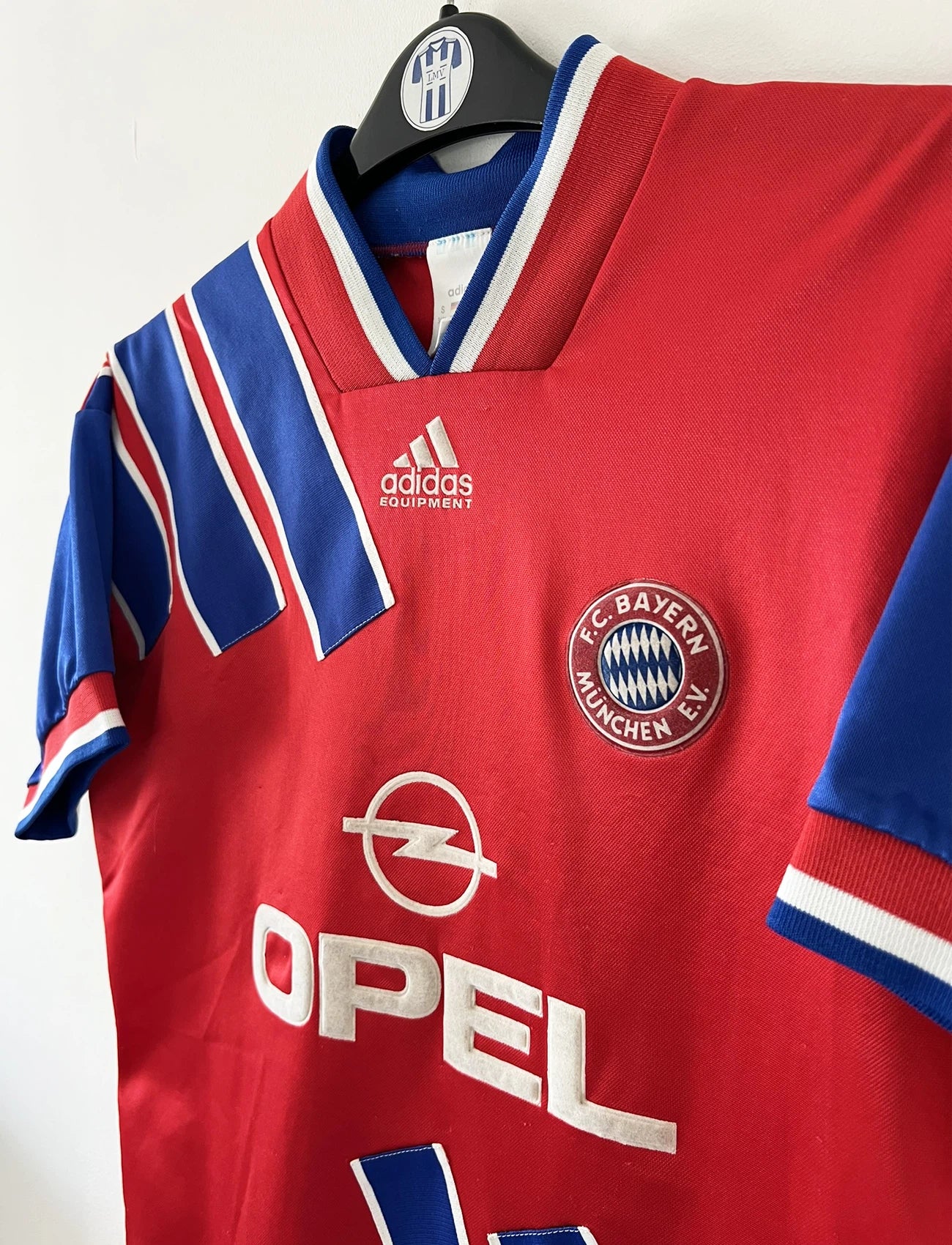 Maillot de foot vintage domicile rouge et bleu du Bayern Munich de la saison 1993-1994. On peut retrouver l'équipementier Adidas et le sponsor Opel. Il s'agit d'un maillot authentique d'époque.