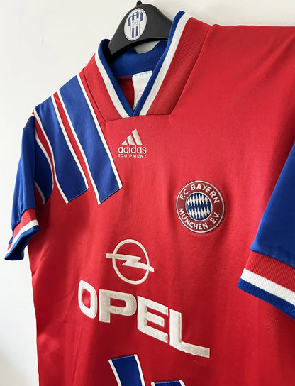 Maillot de foot vintage domicile rouge et bleu du Bayern Munich de la saison 1993-1994. On peut retrouver l'équipementier Adidas et le sponsor Opel. Il s'agit d'un maillot authentique d'époque.