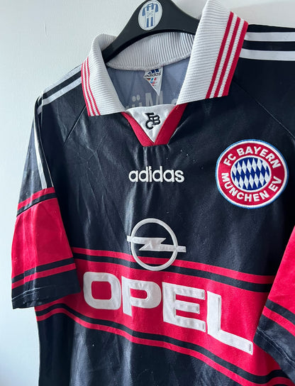 Maillot de foot vintage domicile noir du bayern 1997/1998. On peut retrouver l'équipementier Adidas et le sponsor Opel. Il s'agit d'un maillot authentique d'époque.