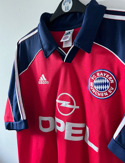 Maillot de foot vintage domicile rouge du Bayern Munich 1999/2001. On peut retrouver l'équipementier Adidas et le sponsor Opel. Le maillot est floqué du numero 3 Bixente Lizarazu. Il s'agit d'un maillot authentique d'époque.