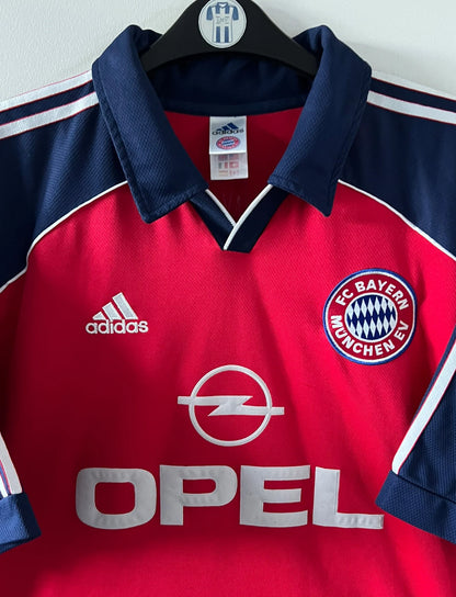 Maillot de foot vintage domicile rouge du Bayern Munich 1999/2001. On peut retrouver l'équipementier Adidas et le sponsor Opel. Le maillot est floqué du numero 3 Bixente Lizarazu. Il s'agit d'un maillot authentique d'époque.