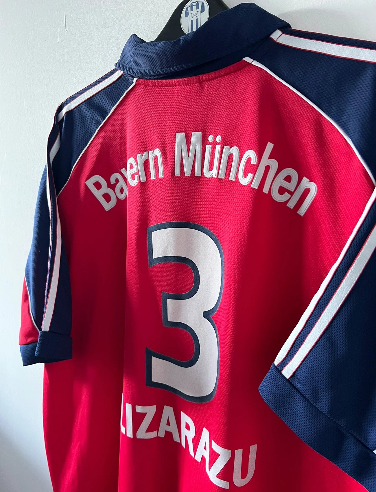 Maillot de foot vintage domicile rouge du Bayern Munich 1999/2001. On peut retrouver l'équipementier Adidas et le sponsor Opel. Le maillot est floqué du numero 3 Bixente Lizarazu. Il s'agit d'un maillot authentique d'époque.