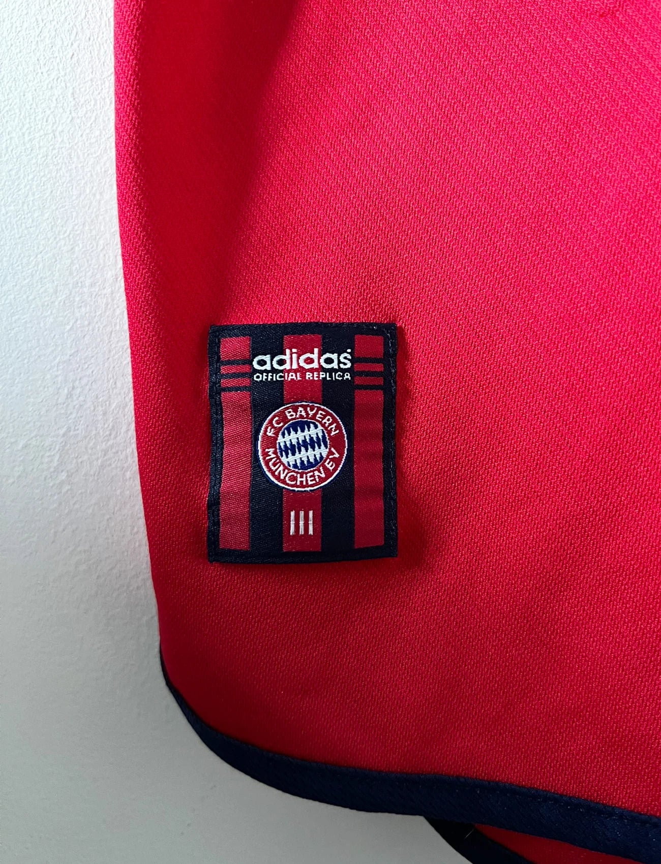 Maillot de foot vintage domicile rouge du Bayern Munich 1999/2001. On peut retrouver l'équipementier Adidas et le sponsor Opel. Le maillot est floqué du numero 3 Bixente Lizarazu. Il s'agit d'un maillot authentique d'époque.