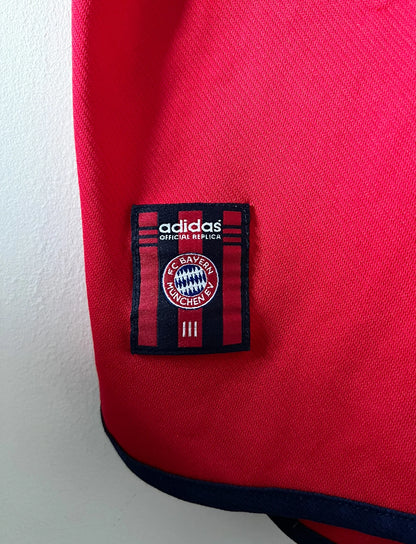 Maillot de foot vintage domicile rouge du Bayern Munich 1999/2001. On peut retrouver l'équipementier Adidas et le sponsor Opel. Le maillot est floqué du numero 3 Bixente Lizarazu. Il s'agit d'un maillot authentique d'époque.