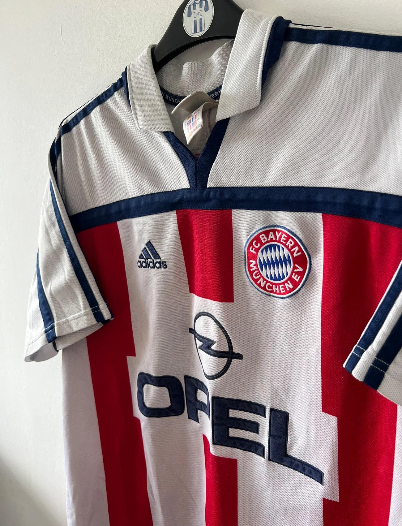 Maillot de foot vintage extérieur blanc et rouge du Bayern Munich 2000/2002. On peut retrouver l'équipementier Adidas et le sponsor Opel. Il s'agit d'un maillot authentique d'époque.