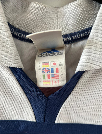 Maillot de foot vintage extérieur blanc et rouge du Bayern Munich 2000/2002. On peut retrouver l'équipementier Adidas et le sponsor Opel. Il s'agit d'un maillot authentique d'époque.