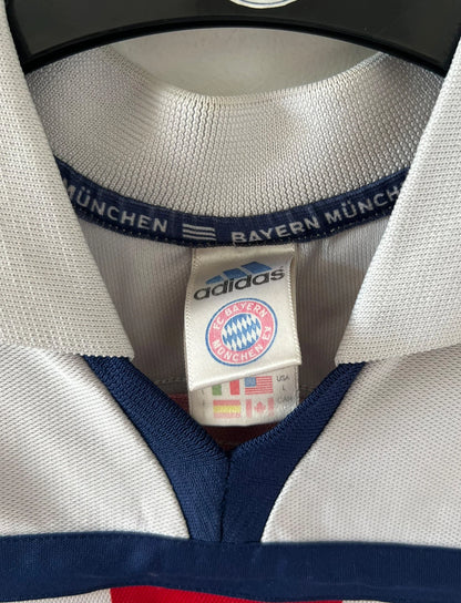 Maillot de foot vintage extérieur blanc et rouge du Bayern Munich 2000/2002. On peut retrouver l'équipementier Adidas et le sponsor Opel. Il s'agit d'un maillot authentique d'époque.