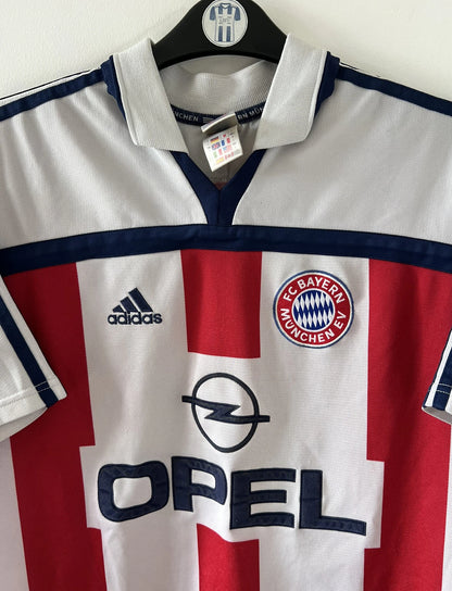 Maillot de foot vintage extérieur blanc et rouge du Bayern Munich 2000/2002. On peut retrouver l'équipementier Adidas et le sponsor Opel. Il s'agit d'un maillot authentique d'époque.