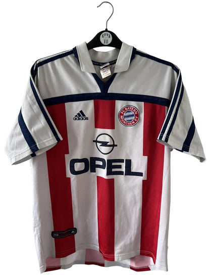 Maillot de foot vintage extérieur blanc et rouge du Bayern Munich 2000/2002. On peut retrouver l'équipementier Adidas et le sponsor Opel. Il s'agit d'un maillot authentique d'époque.