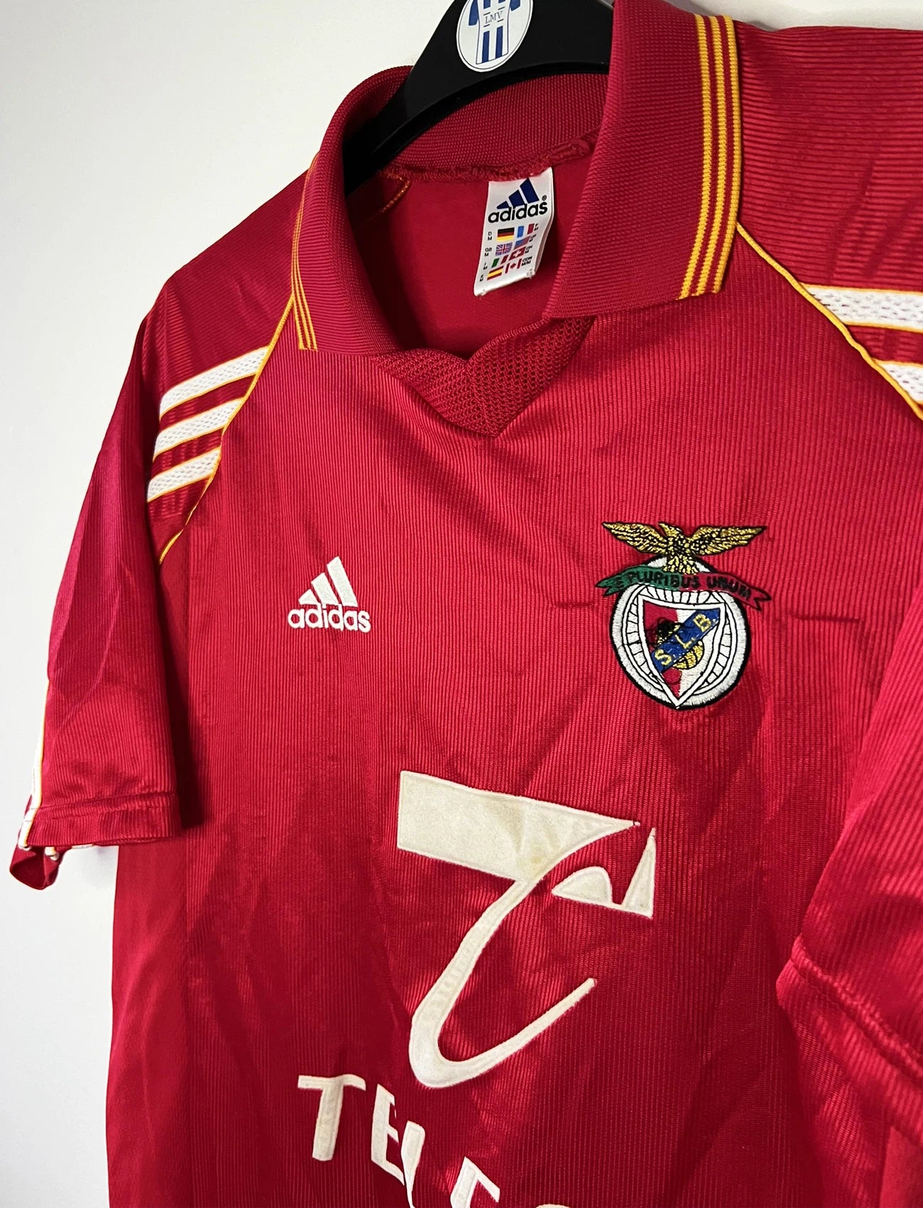 Maillot de foot vintage domicile rouge du Benfica de la saison 1998/1999. On peut retrouver l'équipementier Adidas et le sponsor Telecel. Il s'agit d'un maillot authentique d'époque.