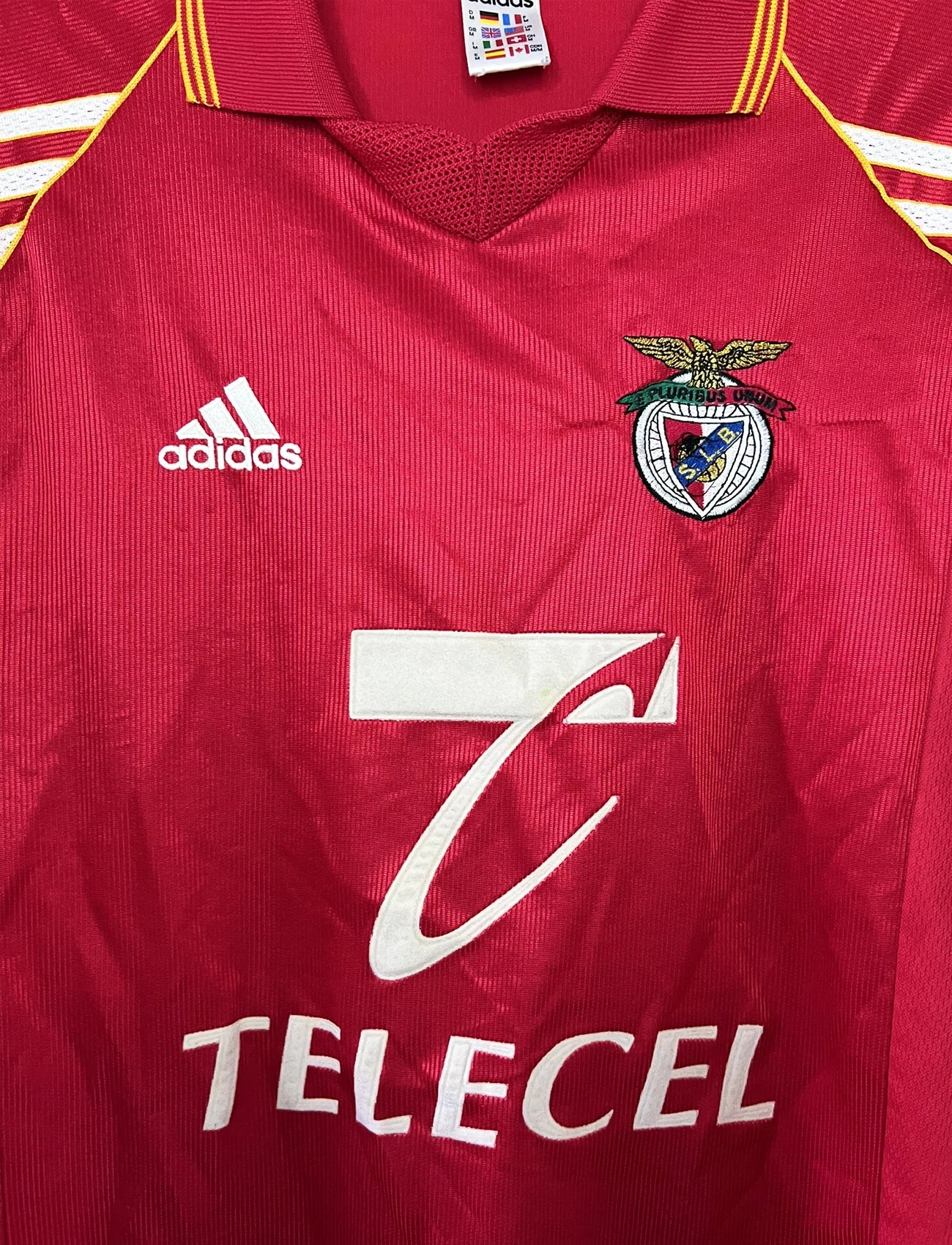 Maillot de foot vintage domicile rouge du Benfica de la saison 1998/1999. On peut retrouver l'équipementier Adidas et le sponsor Telecel. Il s'agit d'un maillot authentique d'époque.