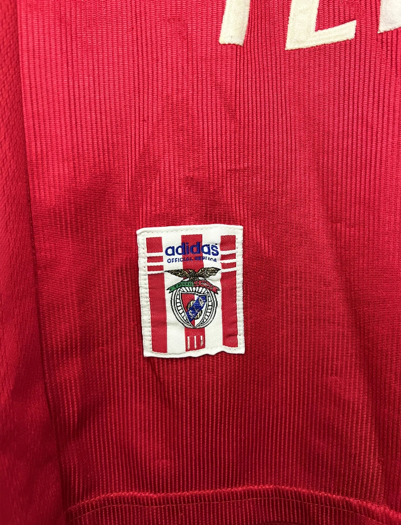 Maillot de foot vintage domicile rouge du Benfica de la saison 1998/1999. On peut retrouver l'équipementier Adidas et le sponsor Telecel. Il s'agit d'un maillot authentique d'époque.