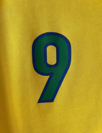 Maillot de foot vintage domicile jaune du Brésil 1998. On peut retrouver l'équipementier Nike. Le maillot est floqué du numéro 9 Ronaldo. Il s'agit d'un maillot authentique d'époque.