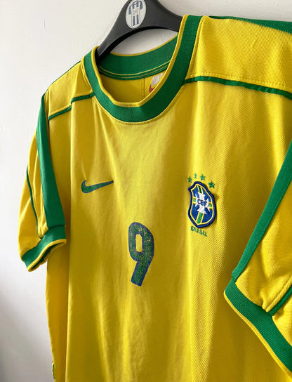 Maillot de foot vintage domicile jaune du Brésil 1998. On peut retrouver l'équipementier Nike. Le maillot est floqué du numéro 9 Ronaldo. Il s'agit d'un maillot authentique d'époque.