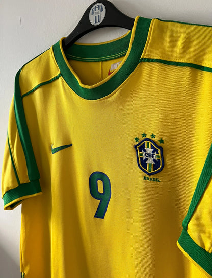 Maillot de foot vintage domicile jaune du Brésil 1998. On peut retrouver l'équipementier Nike. Le maillot est floqué du numéro 9 Ronaldo. Il s'agit d'un maillot authentique d'époque.